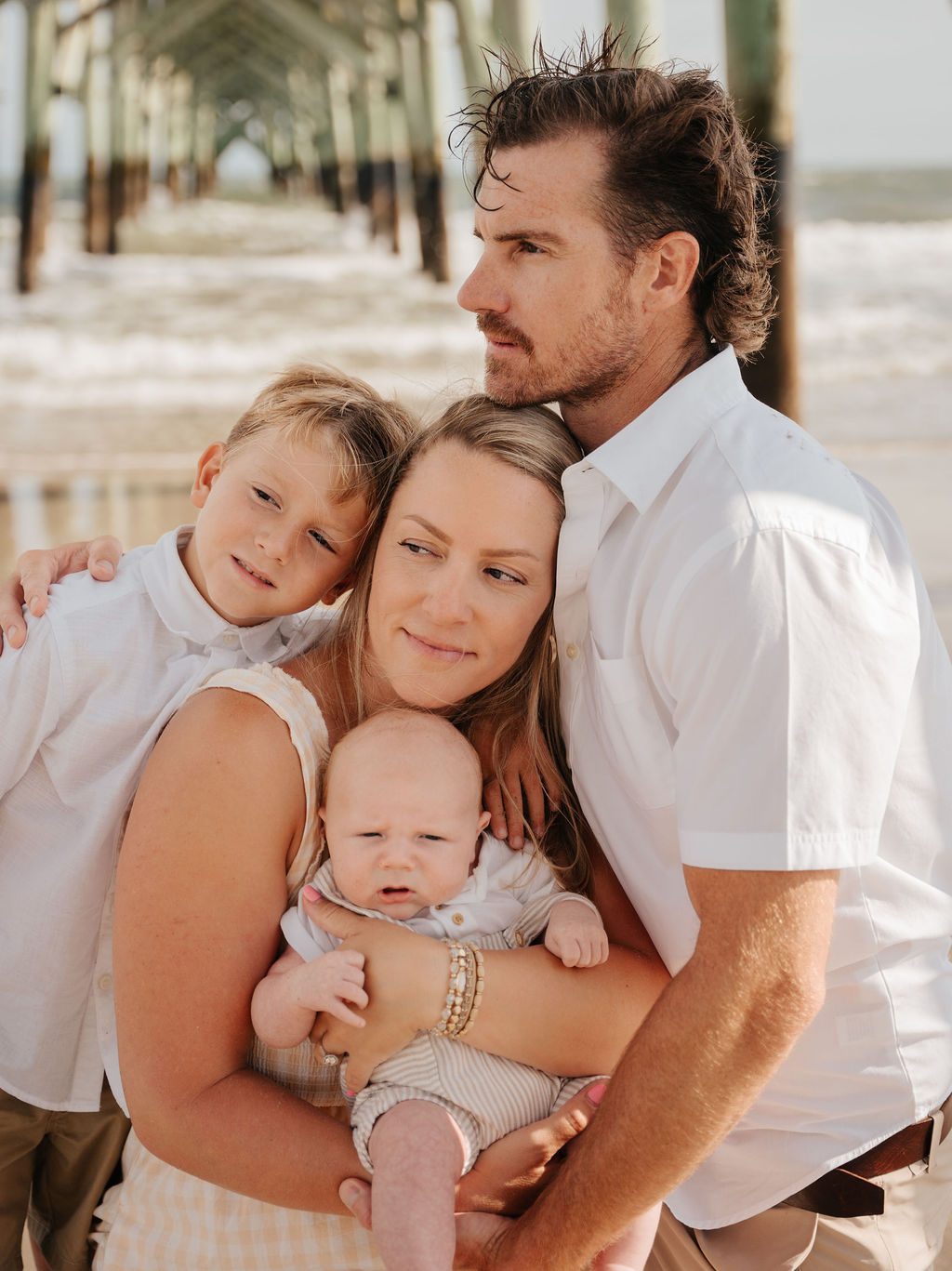 Family of four gathered close together under the pier