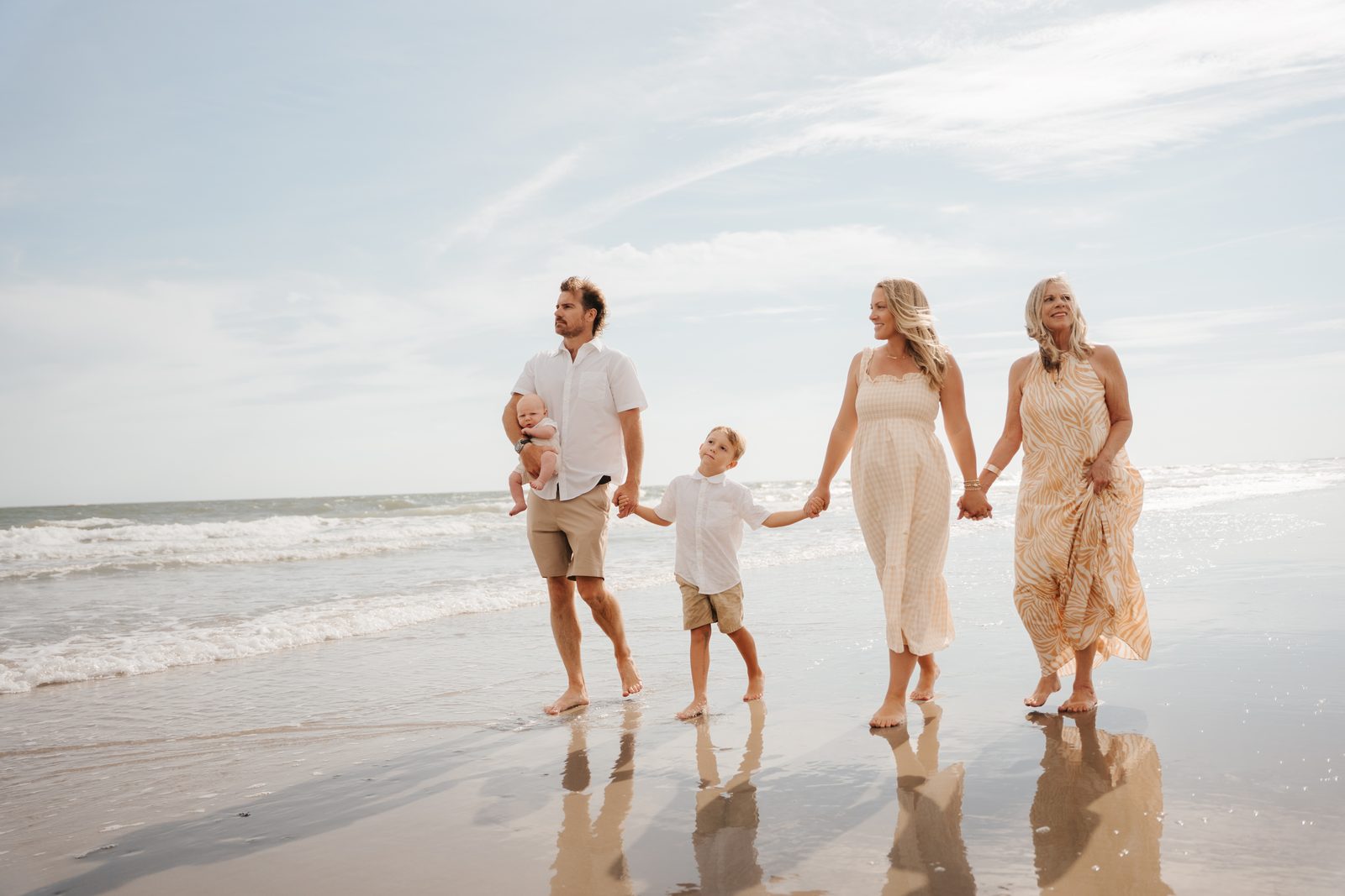 The whole family walking hand in hand along the shoreline, three generations together