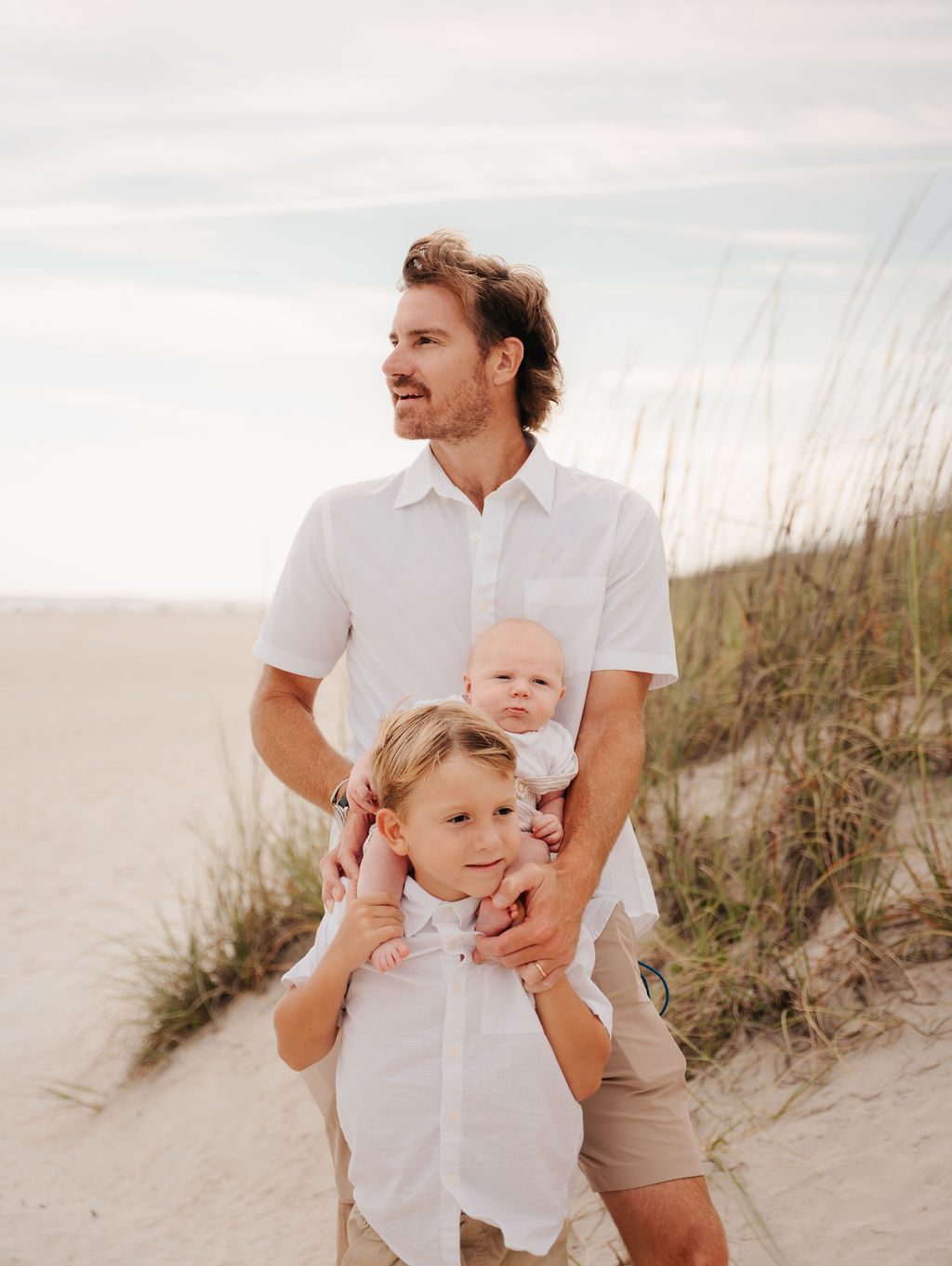 Father crouching on the sand with his baby and young son