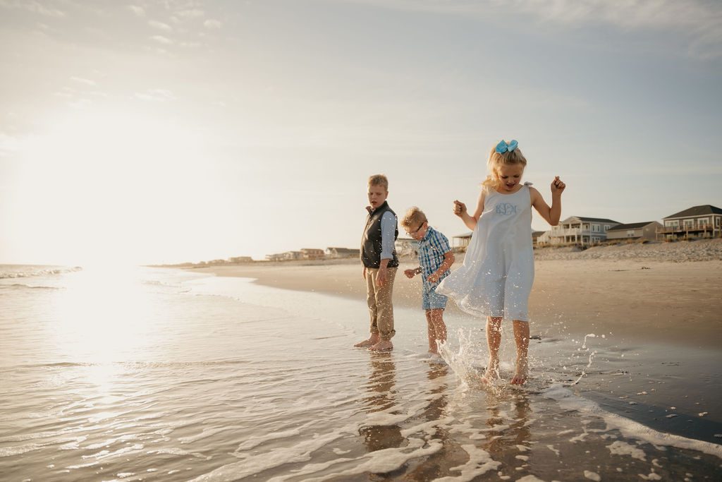 Three children running and splashing at the water's edge