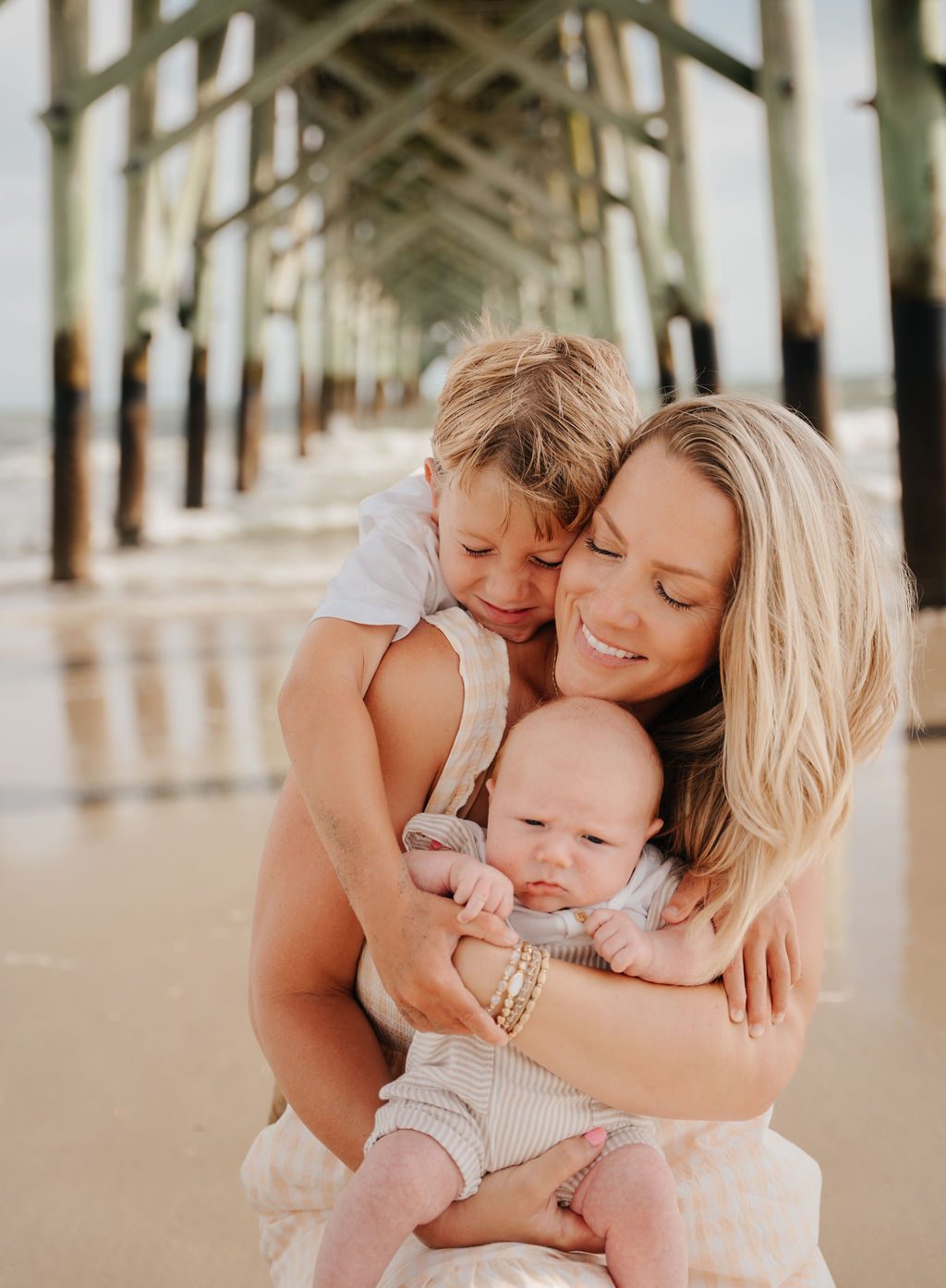 Mother holding her baby and older son beneath the pier