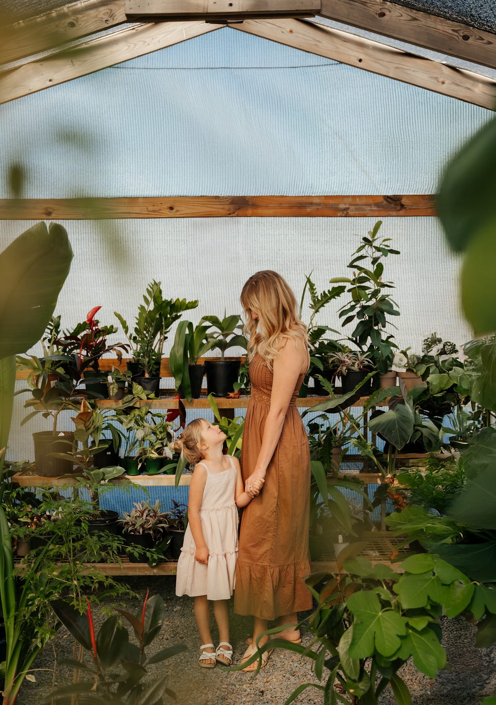 Mother and daughter standing together looking at each other in the greenhouse