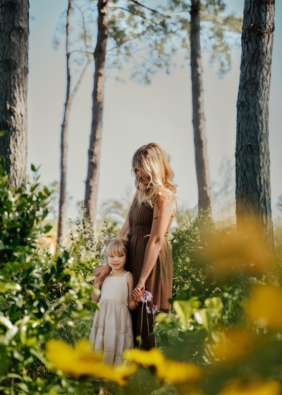 Mother and daughter holding hands beneath the pines