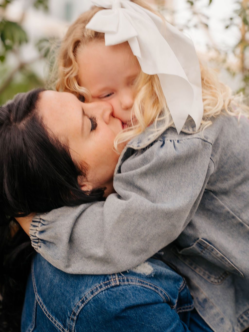 Mother kissing her daughter on the cheek in the greenhouse