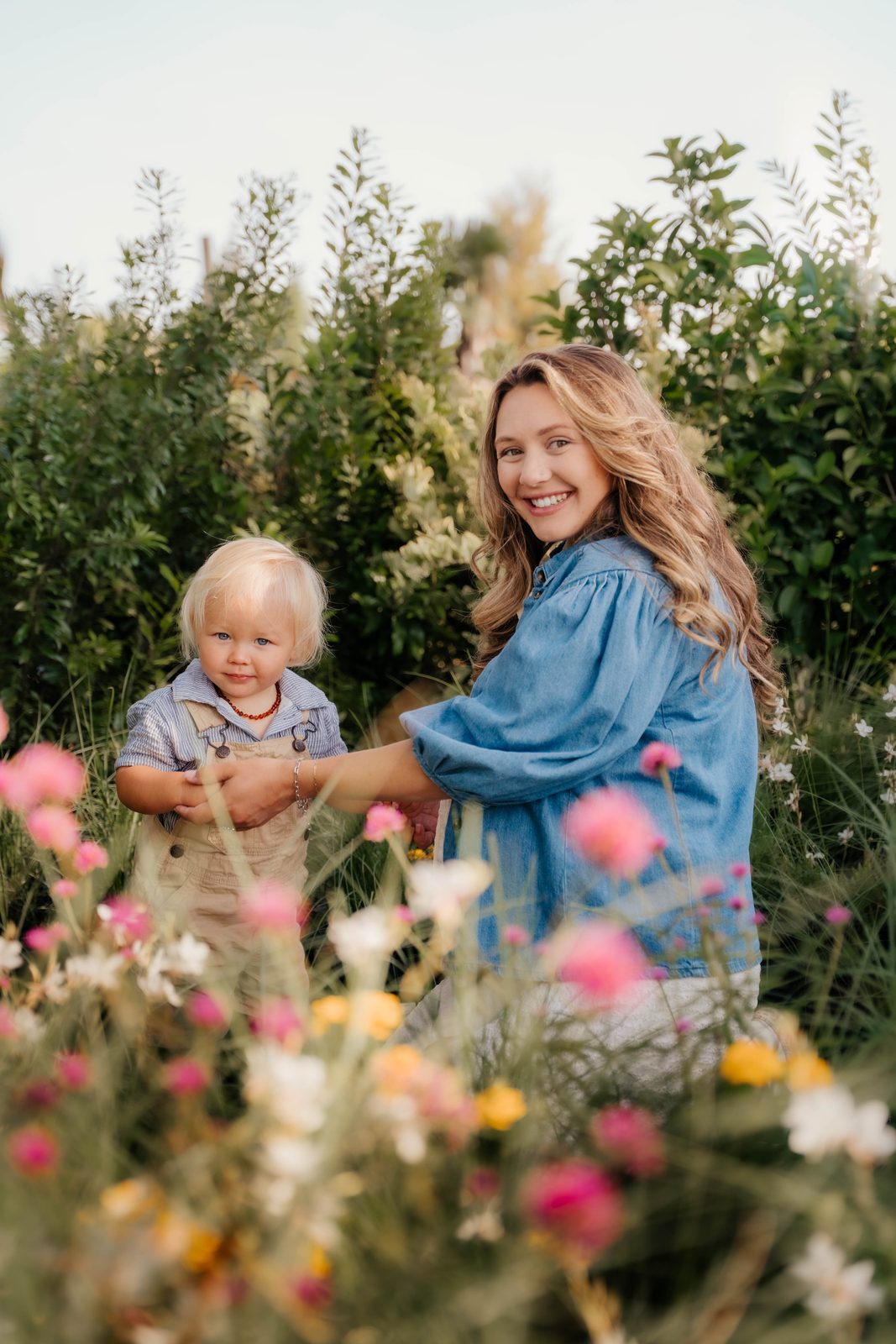 Mother and toddler standing together in a field of pink and yellow wildflowers
