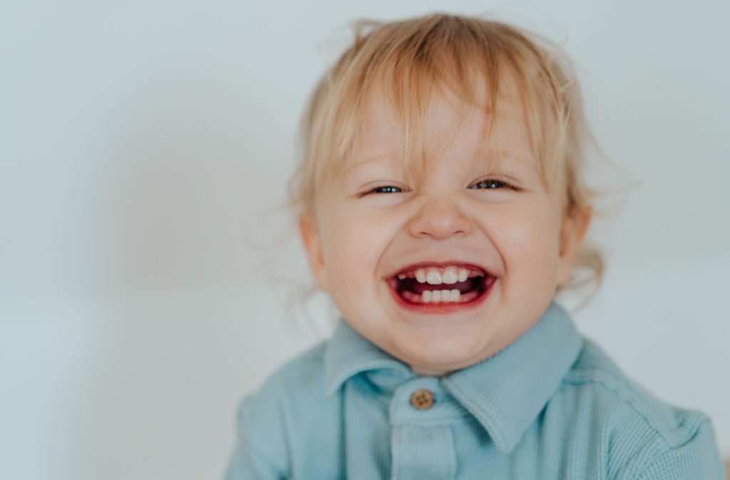 Blonde toddler laughing with his whole face