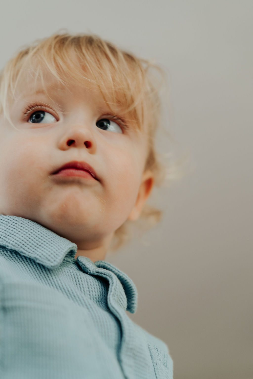 Blonde toddler looking up and away in soft window light