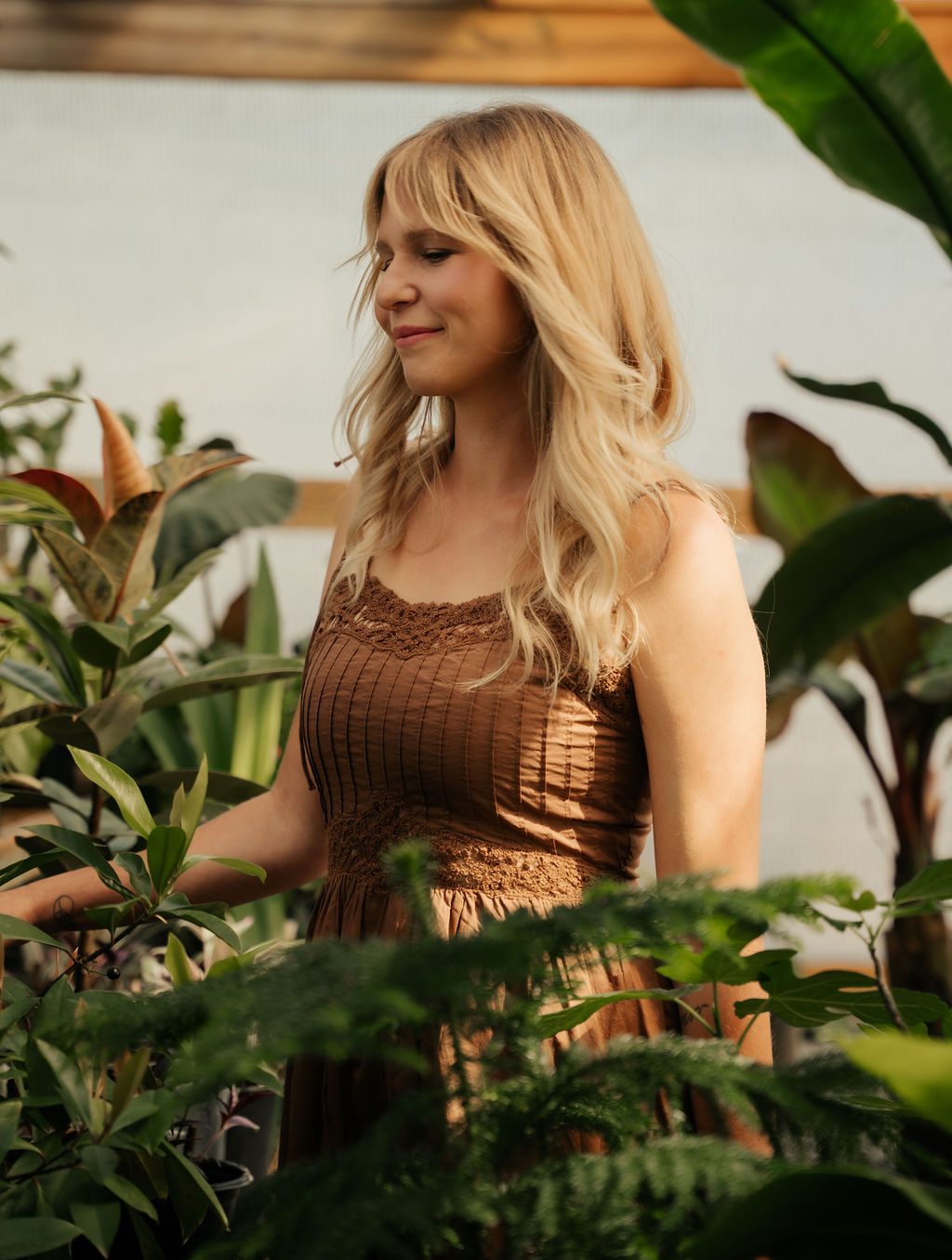 Woman in a brown dress standing among the greenhouse plants